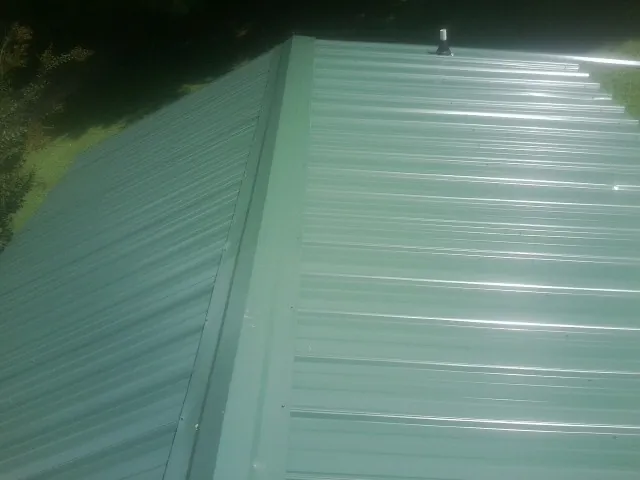 New green metal panels meeting at the ridge of a roof — Flat Roof Repair work by our crew in Burbank